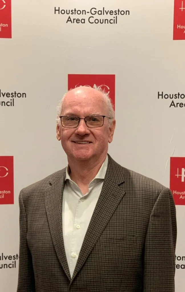Picture of older white male with glasses in a blazer and white button down shirt smiling